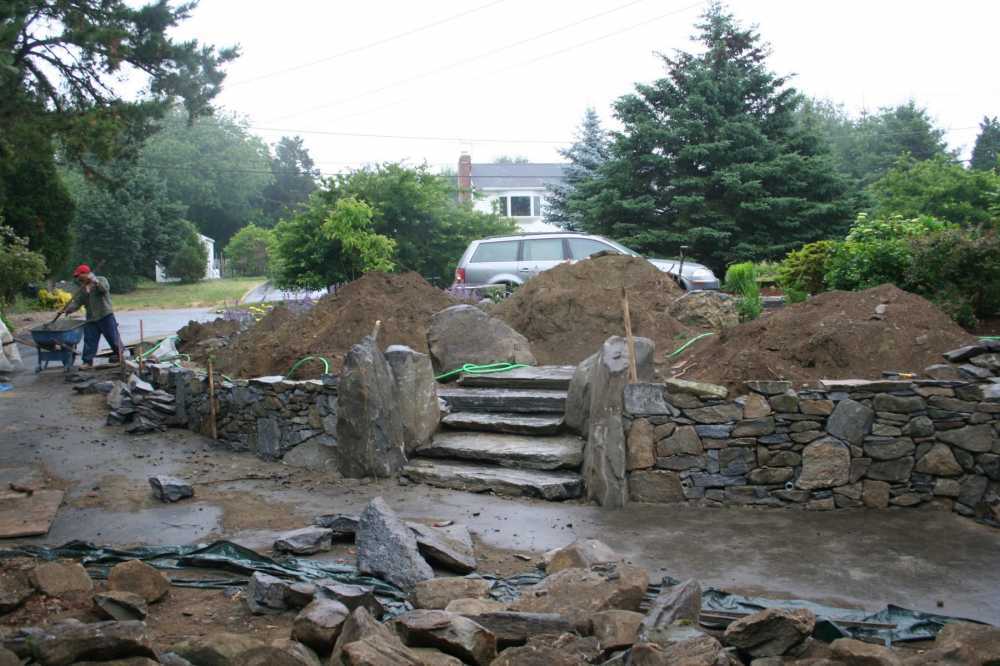 Slab steps cut through this retaining wall.  Boulders help anchor and soften the wall ends.